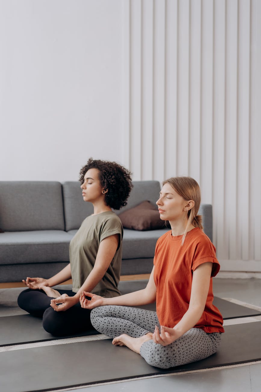 Woman in a calm, seated yoga pose in a dark, minimalist room.